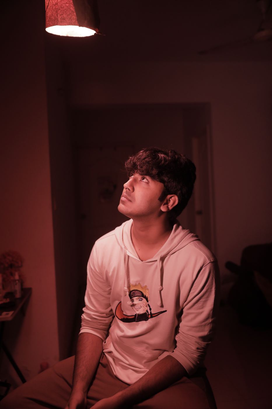 Chiraag sitting in warm red light, looking upward