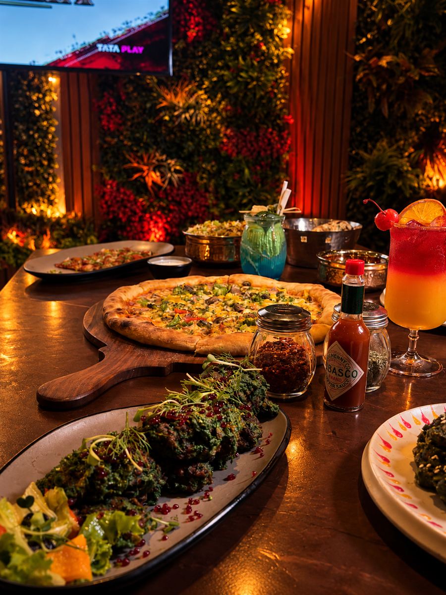 A spread of pizza, kebabs and cocktails on a wooden table