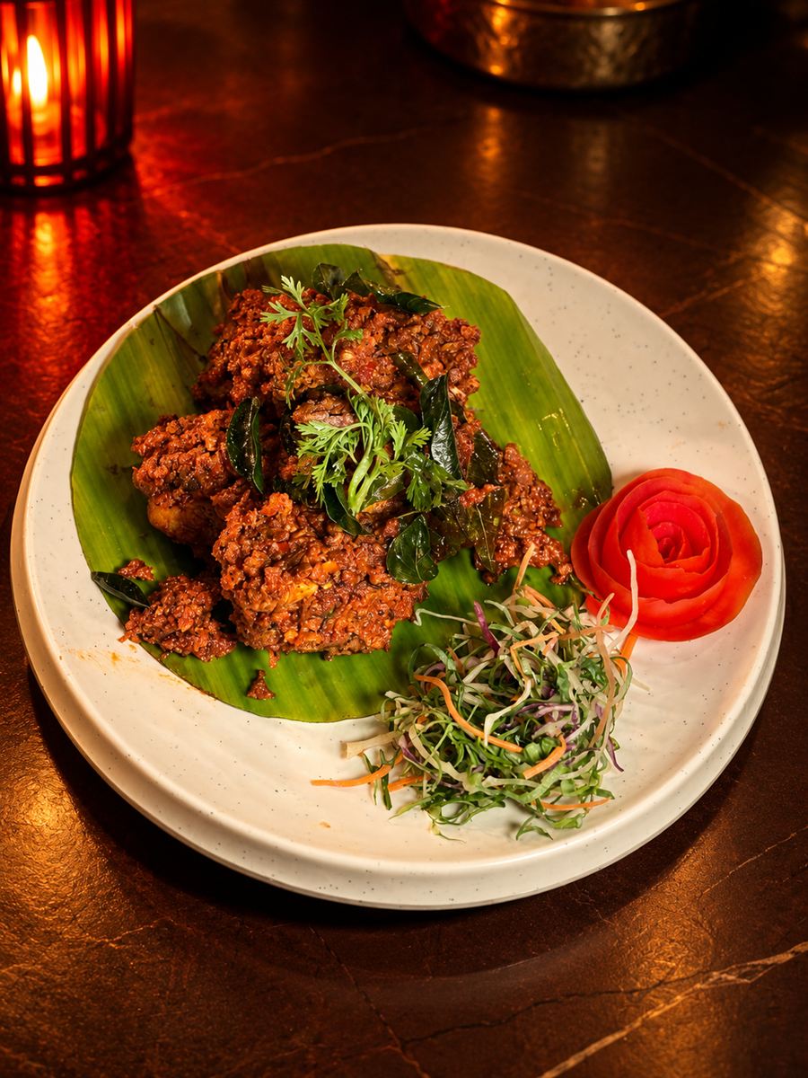 Grilled kebabs on a banana leaf with a tomato rose garnish