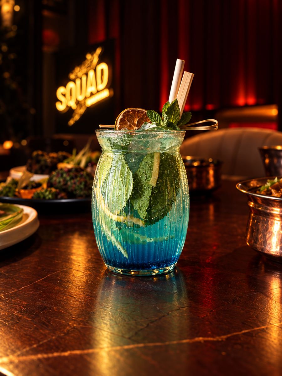 Blue layered mocktail with mint in front of the Squad sign