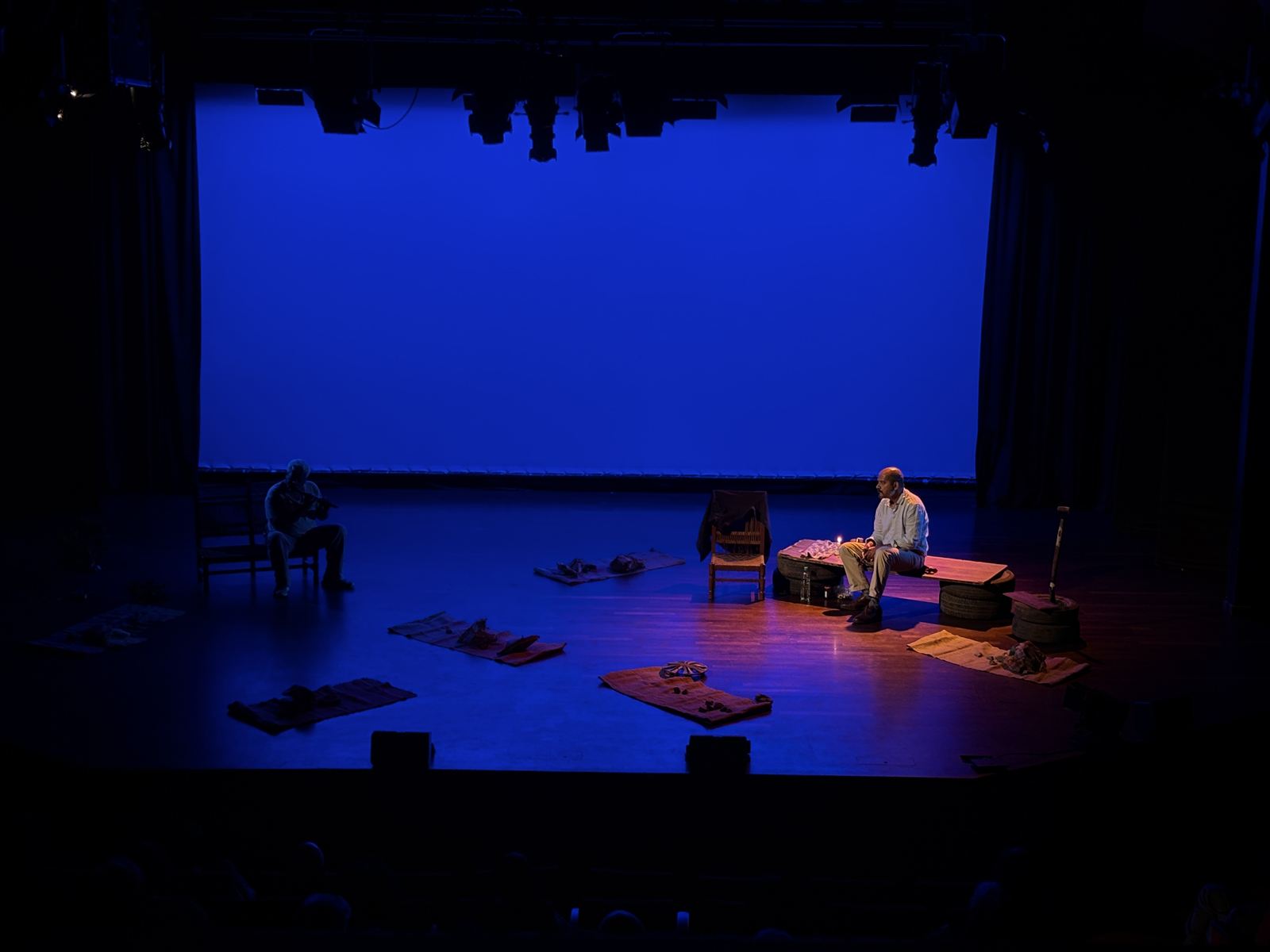 Wide view of a stage lit in deep blue with warm pools of light