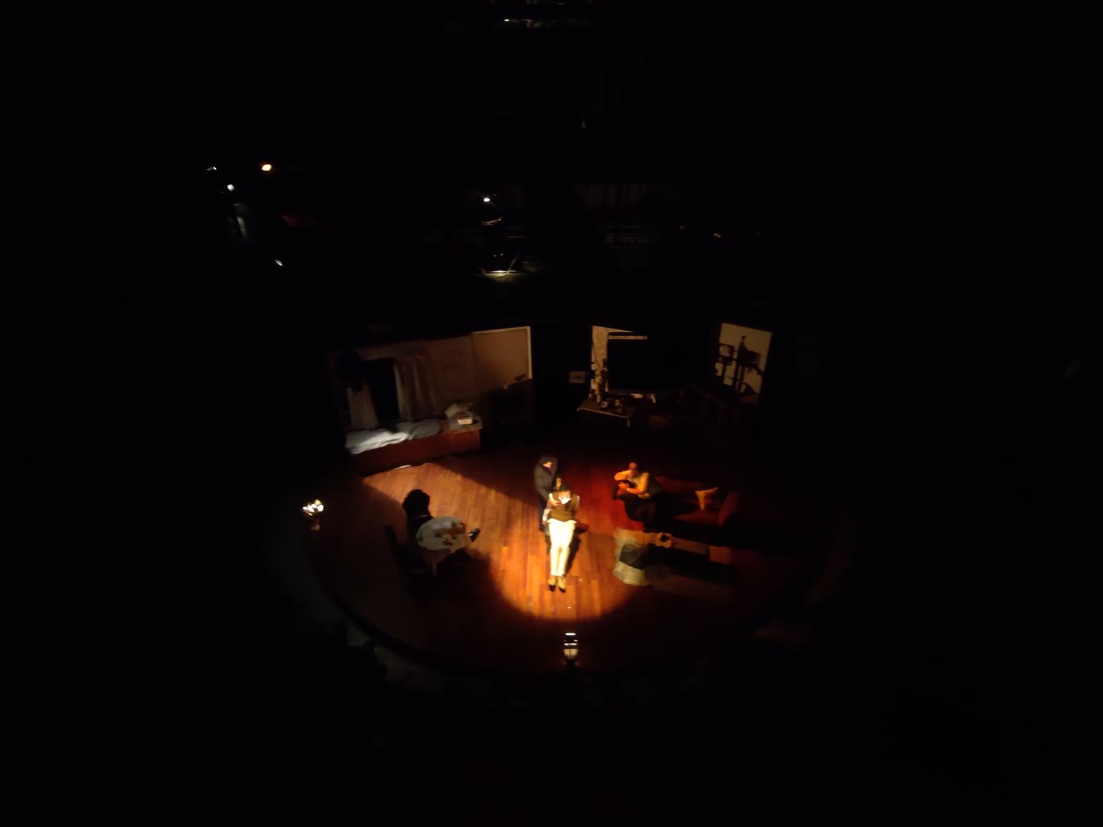 Performers in a single warm pool of light on a dark stage